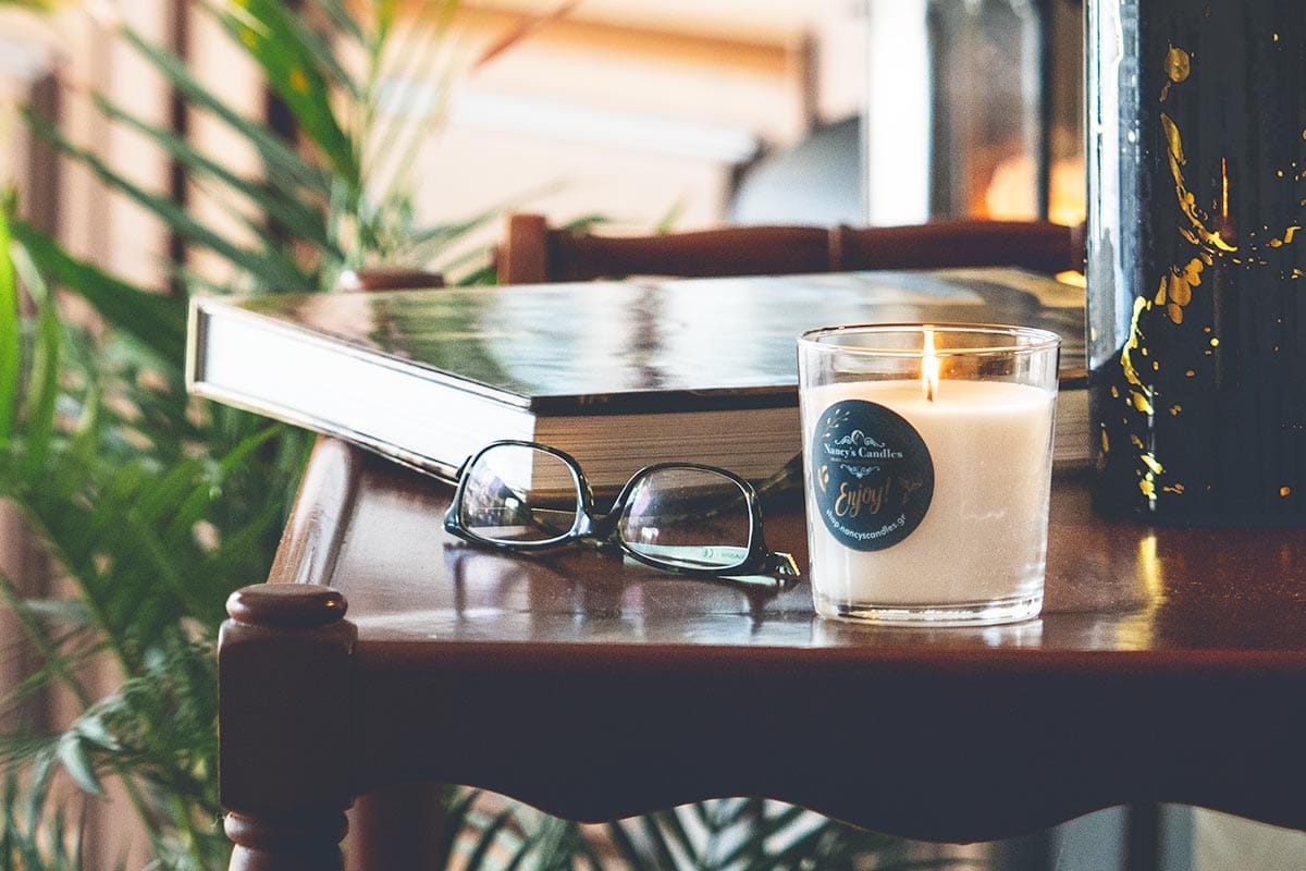 Κερί, βιβλίο και γυαλιά σε ξύλινο τραπέζι.