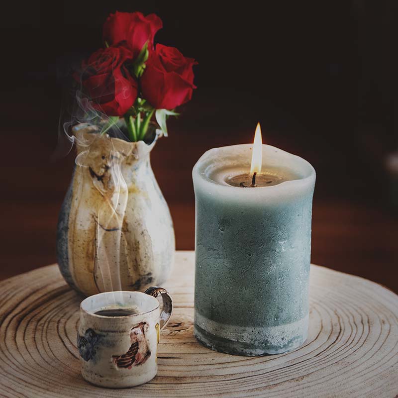 Κερί, λουλούδια, ατμός καφέ σε ξύλινη επιφάνεια.