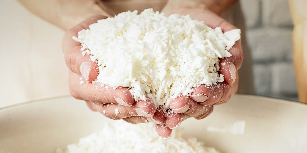 Χέρια κρατούν τριμμένο λευκό σαπούνι