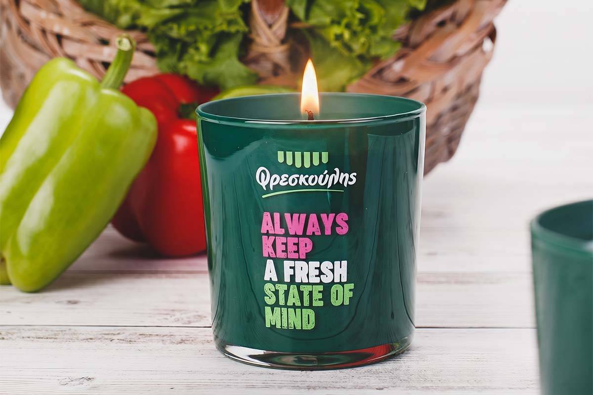 Αναμμένο χειροποίητο κερί Nancy's Candles με λογότυπο σε πράσινο βαμμένο εσωτερικά δοχείο για το εταιρικό δώρο της Eurocatering Φρεσκούλης