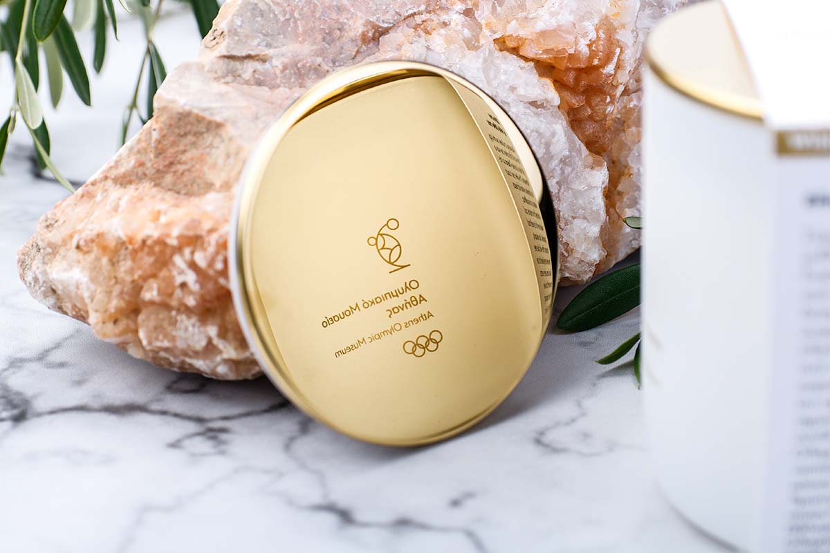 Premium αρωματικό κερί Nancy's Candles με λαμπερό χρυσό καπάκι-καθρέφτη που καθρεφτίζει το λογότυπο του Ολυμπιακού Μουσείου Αθήνας